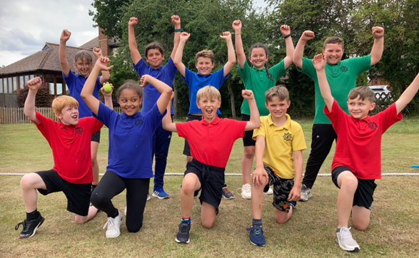 a team of children wearing primary colours and raising their arms in victory